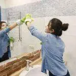 Sprzątanie Gdańsk, Gdynia, Sopot - Trójmiasto i okolice - Kobieta sprzątająca łazienkę zieloną rękawiczką w Trójmieście i okolicach.