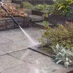 Sprzątanie Gdańsk, Gdynia, Sopot - Trójmiasto i okolice - Mężczyzna spryskuje ogród myjką ciśnieniową.