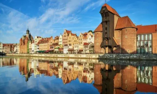 Sprzątanie Gdańsk, Gdynia, Sopot - Trójmiasto i okolice - Historyczne nabrzeże w Trójmieście ze starymi ceglanymi budynkami i charakterystycznym drewnianym dźwigiem odbijającym się w spokojnej rzece pod czystym, błękitnym niebem. Sprzątanie Gdańsk, Gdynia, Sopot - Trójmiasto i okolice - Historyczne nabrzeże w Trójmieście ze starymi ceglanymi budynkami i charakterystycznym drewnianym dźwigiem odbijającym się w spokojnej rzece pod czystym, błękitnym niebem.